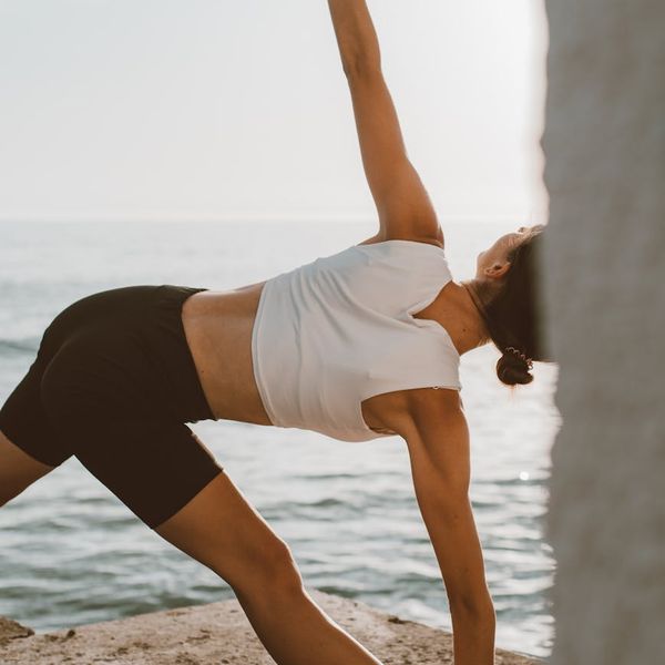 Person doing a stretching yoga pose against a sunrise background.